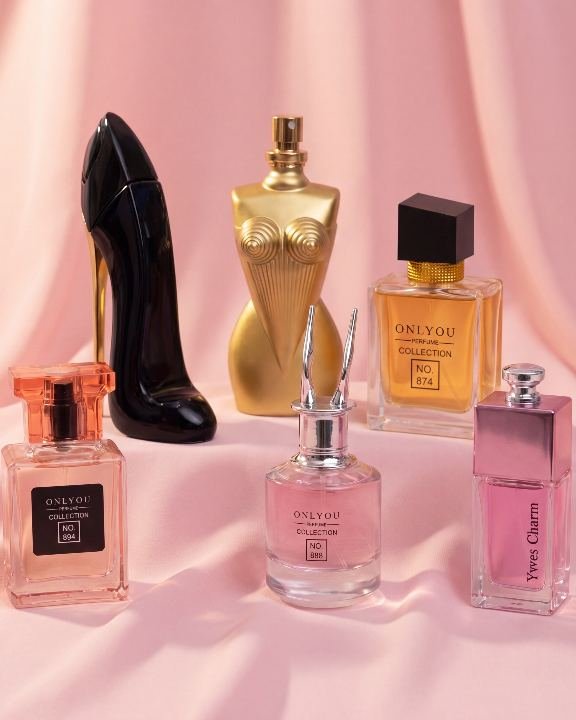 Collection de flacons de parfum posés sur un drapé rose