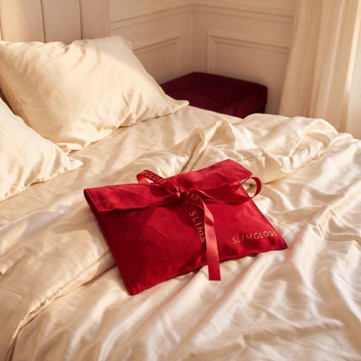 Pochette en satin rouge posée sur un lit en satin crème