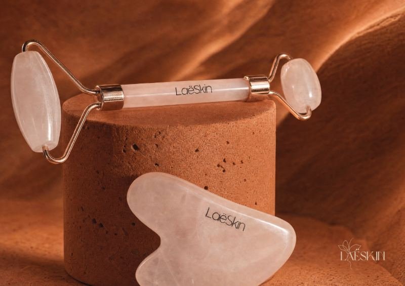 Rouleau et gua sha en quartz rose Laëskin sur un socle terre cuite